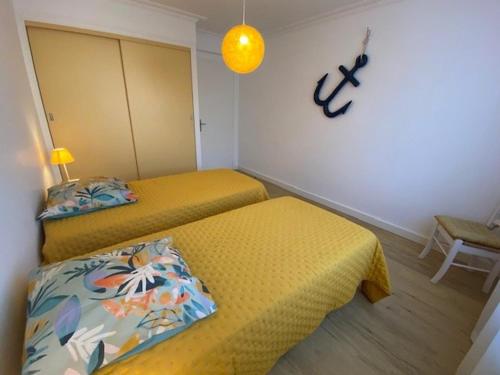 pokój z dwoma łóżkami i pomarańczową lampą w obiekcie Appartement rénové 85m2, terrasse, parking, face à plage - FR-1-494-149 w mieście Royan