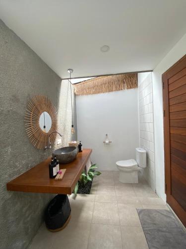a bathroom with a sink and a toilet and a mirror at Suku Lifestyle Hotel & Villas in Selong Belanak