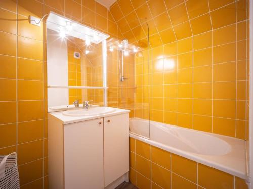 y baño con azulejos de color naranja, lavabo y bañera. en Appartement Peyragudes, 3 pièces, 6 personnes - FR-1-695-20, en Germ