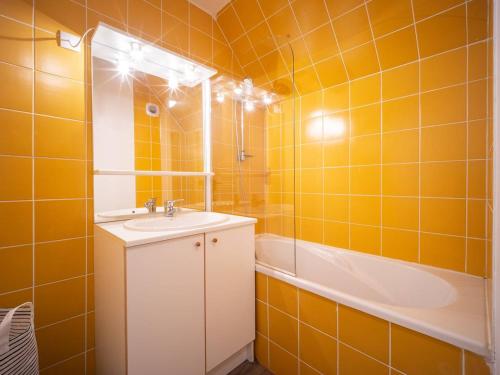 La salle de bains est pourvue de carrelage orange, d'un lavabo et d'une baignoire. dans l'établissement Duplex rénové 6 pers, balcon, casier à skis, parking gratuit - FR-1-695-20, à Germ