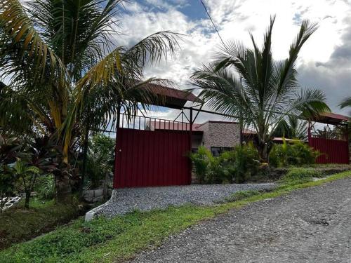 une maison avec une clôture rouge et des palmiers dans l'établissement Villas Altos del Arenal, à Fortuna