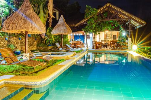 einen Pool mit Stühlen und Sonnenschirmen neben einem Haus in der Unterkunft Marqis Sunrise Sunset Resort and Spa in Baclayon