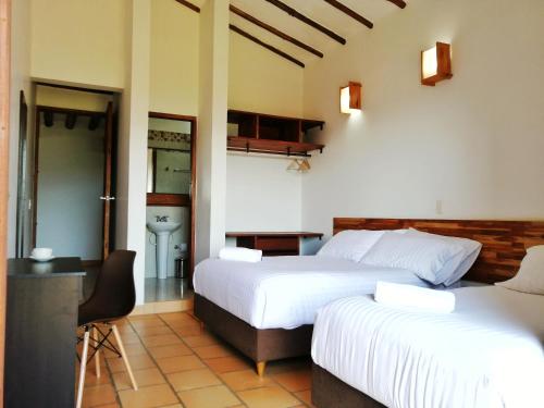 a hotel room with two beds and a bathroom at CASA LLANO HIGUERAS in Barichara