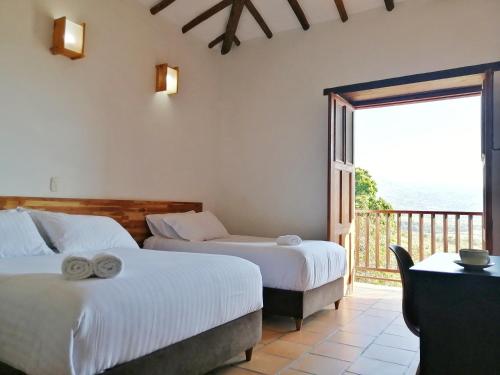 two beds in a room with a balcony at CASA LLANO HIGUERAS in Barichara