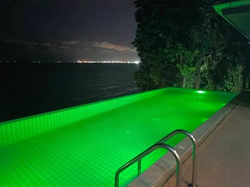 a green swimming pool with the water at night at Eco stay - Luxury pool + Seaview Villa in North Pattaya