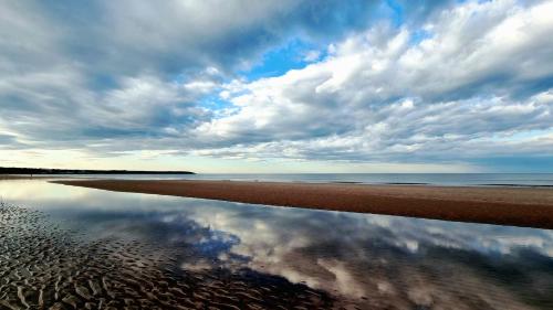 a reflection of the sky in the water on the beach at Seascape Apartment in Filey