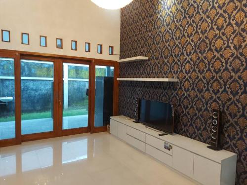 a living room with a flat screen tv on a wall at Tentrem Homestay by FHStay in Sleman