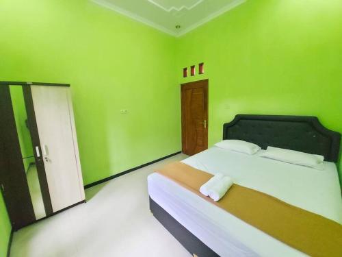 a green bedroom with a bed in a room at Tentrem Homestay by FHStay in Sleman