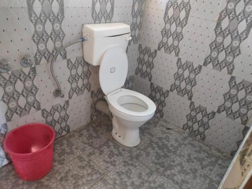 een badkamer met een toilet en een rode emmer bij Snow White Holiday Inn Homestay in Kalimpong