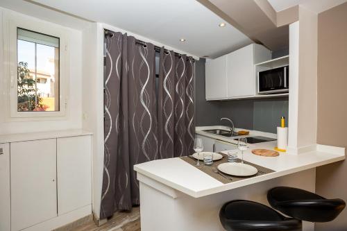 a kitchen with white cabinets and black chairs at Studi'o Soleil in Cannes