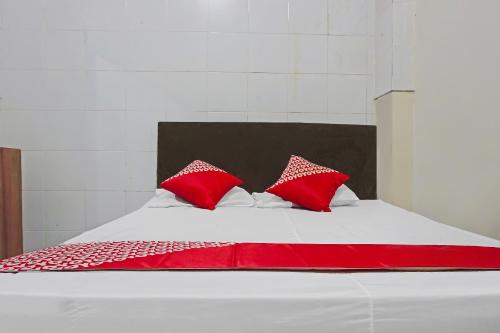 a bed with red pillows on top of it at Hotel O Diamond Inn Makassar in Makassar