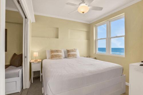 a bedroom with a bed with a ceiling fan and a window at Beachside Surf Haven in Jacksonville Beach