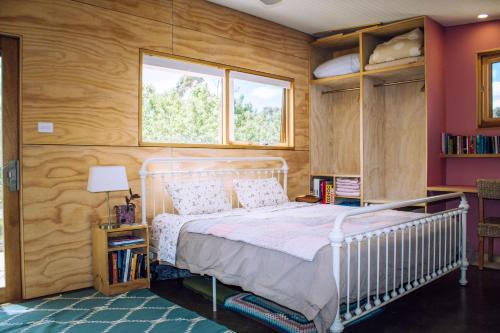 1 dormitorio con cama blanca y paredes de madera en Escape to a Peaceful Eco Studio in Private Garden, en Yapeen