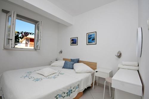 1 dormitorio con 2 camas y ventana en Apartments Maja 100 from the beach, en Podgora