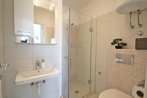 a bathroom with a sink and a glass shower at Apartments Maja 100 from the beach in Podgora
