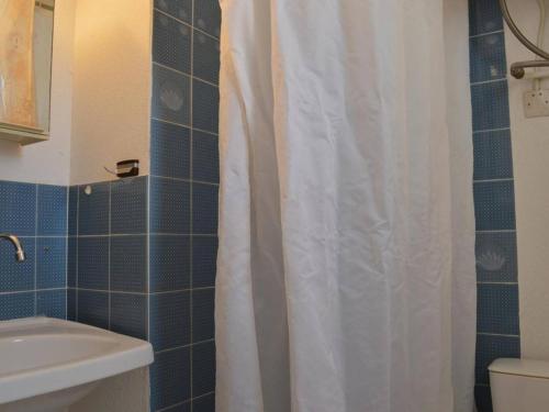 La salle de bains est pourvue d'un rideau de douche blanc et de toilettes. dans l'établissement Studio Cabine avec Piscine, 4 couchages, proche plage et commerces - FR-1-229D-345, à Saint Pierre La Mer
