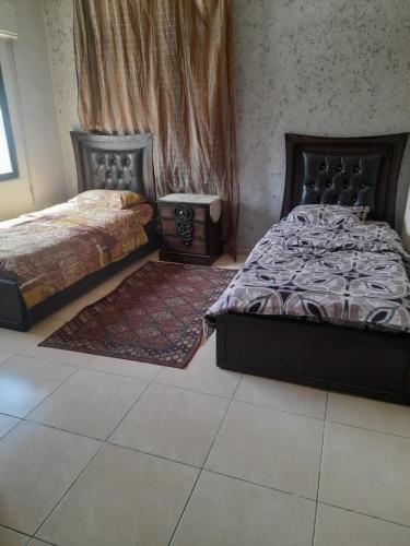 a bedroom with two beds and a rug at Al Karawan Hotel Apartments in Amman