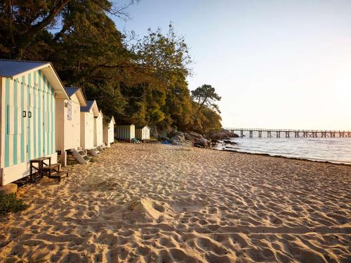 une plage avec une rangée de maisons et une jetée dans l'établissement Studio avec jardinet, proche plage et commerces, La Guérinière - FR-1-224B-594, à La Guérinière