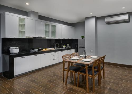 a kitchen with white cabinets and a table and chairs at BIJOU Serviced Residence in Phnom Penh