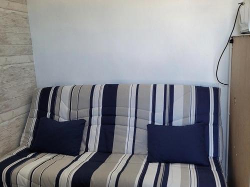 eine gestreifte Couch mit zwei blauen Kissen darauf in der Unterkunft Studio Berck-Plage, 1 pièce, 2 personnes - FR-1-646-12 in Berck-sur-Mer