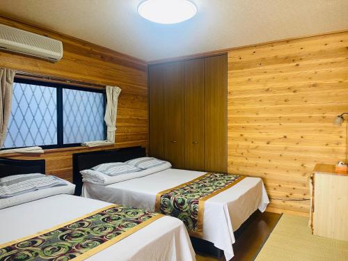2 Betten in einem Zimmer mit Holzwänden in der Unterkunft Biwako AshiのMori 温泉付き in Takashima