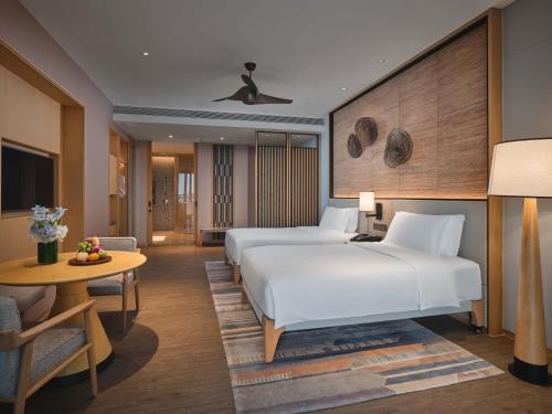 Crowne Plaza Sanya Haitang Bay Resort, an IHG Hotel في سانيا: غرفة فندقية بسريرين وطاولة