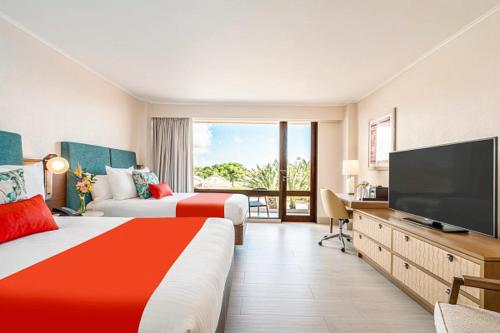 a hotel room with two beds and a flat screen tv at Dreams Curacao Resort, Spa & Casino in Willemstad