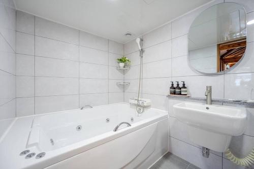 Baño blanco con bañera y lavamanos en Hanokstay Haru en Jeonju