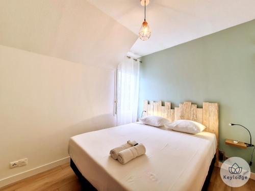 a bedroom with a large white bed with a towel on it at Arbre de Jade, 49 m² joli T3 à la Bretagne in Sainte-Clotilde