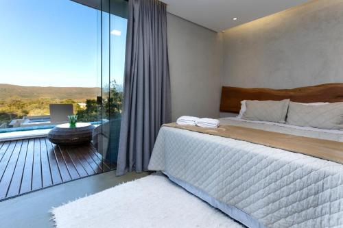 1 dormitorio con 1 cama y balcón con vistas. en Villa Azaleia en Alto Paraíso de Goiás