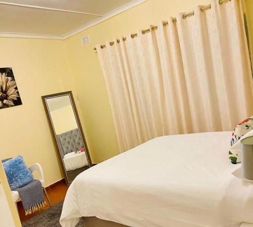 a bedroom with a white bed and a mirror at 25 Swallow Yellowood in Durban