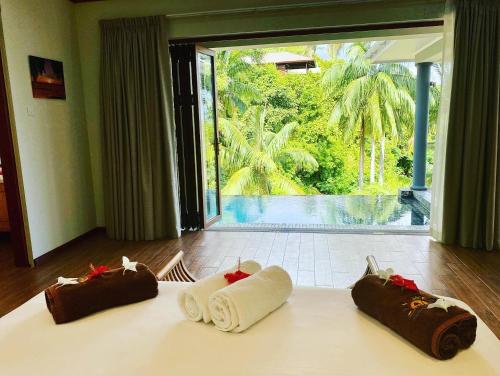 three towels on a bed with a view of a pool at Anse Soleil Beachcomber Hotel and Self Catering in Baie Lazare Mahé