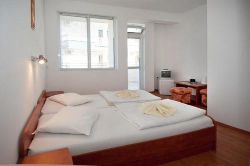 um quarto com uma cama com lençóis brancos e uma janela em Къща за гости Стоянови em Primorsko