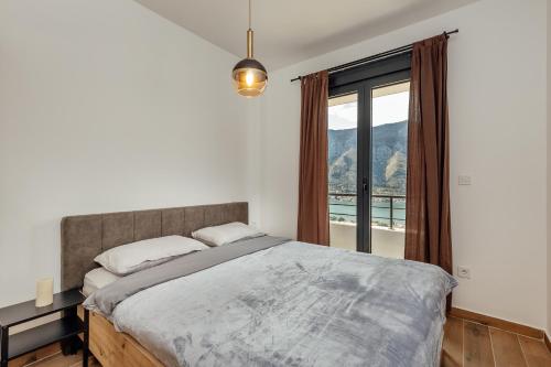 een slaapkamer met een bed en een groot raam bij LANA Sea View Apartment in Kotor
