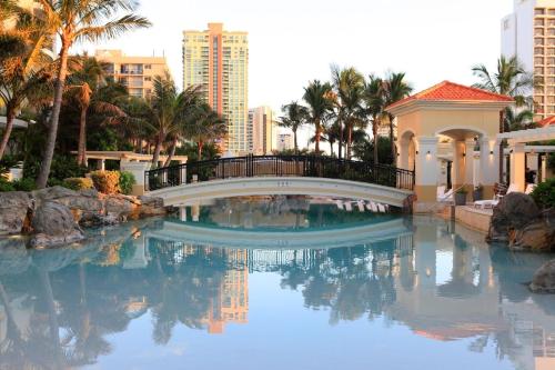 a bridge over a pool with palm trees and buildings at Stunning Apartment Best Ocean Views Surfers in Gold Coast