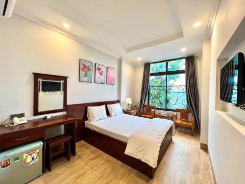 a bedroom with a bed and a desk and a television at Ven Hồ Hotel in Hanoi