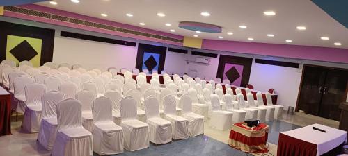 a room with rows of white chairs and a stage at GT Grande Hotel-Near US Consulate in Chennai