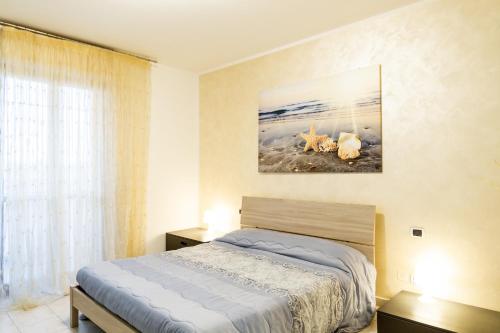 1 dormitorio con 1 cama y una pintura en la pared en Casa Erika, en Puntone di Scarlino