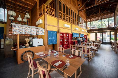 a restaurant with wooden tables and chairs in a room at Onsen at Moncham in Mae Rim