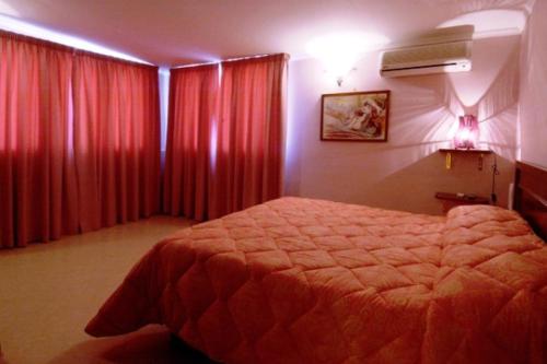 a bedroom with a large bed and red curtains at La Villa Del Patrizio in Ostia Antica