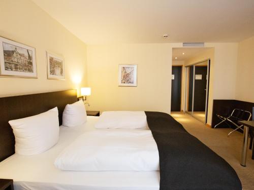 a large white bed in a hotel room at DORMERO Hotel Altes Kaufhaus Lüneburg in Lüneburg