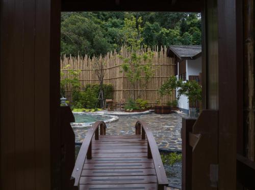 a wooden walkway leading to a backyard with a fence at Onsen at Moncham in Mae Rim
