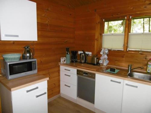 a kitchen with white cabinets and a microwave at Twistesee Ferienhaus 110 in Bad Arolsen