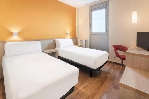 a hotel room with two beds and a chair at Hotel 280 Zaragoza in Calatorao