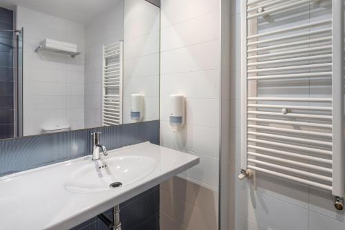 Baño blanco con lavabo y espejo en Hotel 280 Zaragoza, en Calatorao