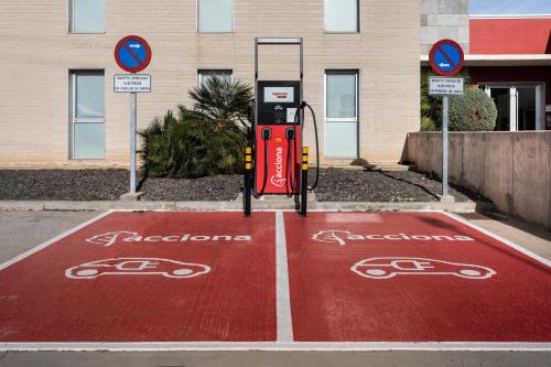 a parking lot with a red gas pump in front of a building at Hotel 280 Zaragoza in Calatorao