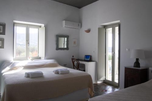a white bedroom with two beds and two windows at Armira seaside house in Antiparos