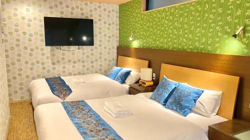 a hotel room with two beds and a flat screen tv at One More Heart Fushimi Inari in Momoyama-chō
