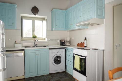 a kitchen with blue cabinets and a washing machine at Armira seaside house in Antiparos
