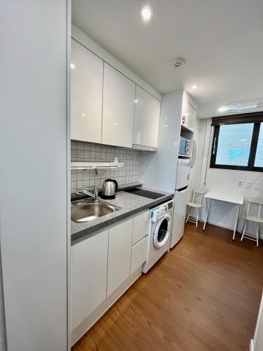 a white kitchen with a sink and a dishwasher at 318 Stay in Seoul